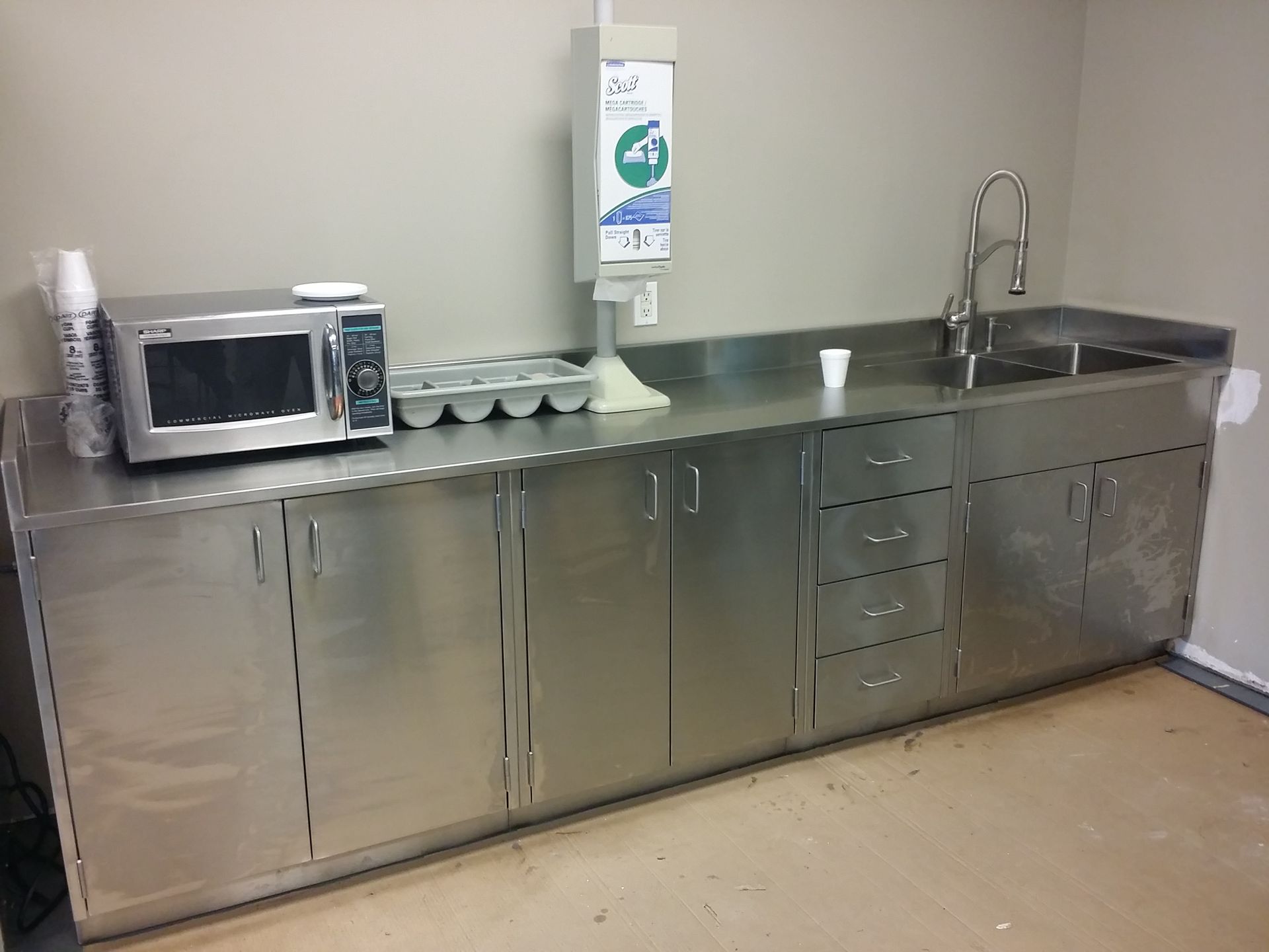 A kitchen with stainless steel cabinets and a microwave and sink
