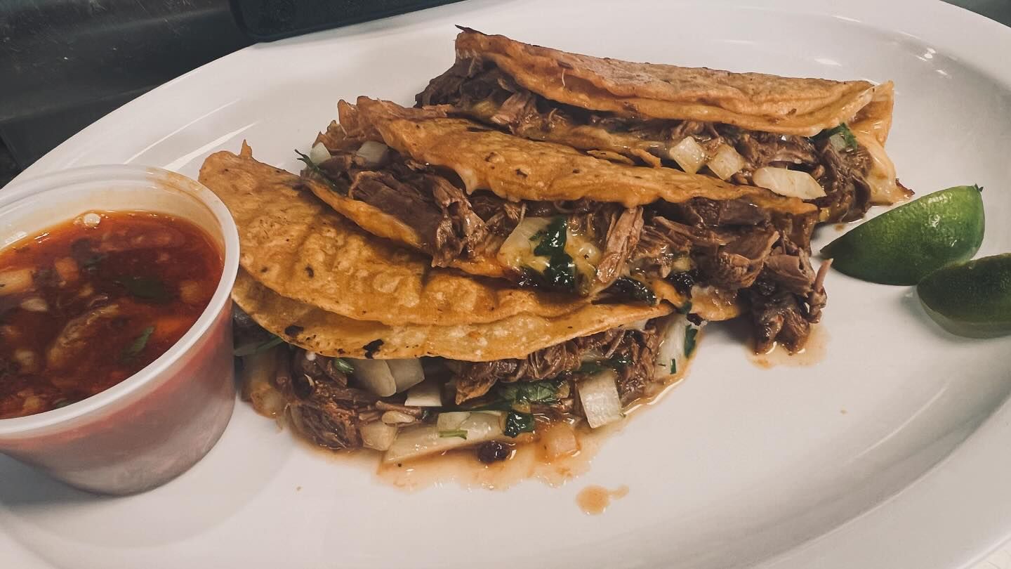 A white plate topped with tacos and a cup of salsa.