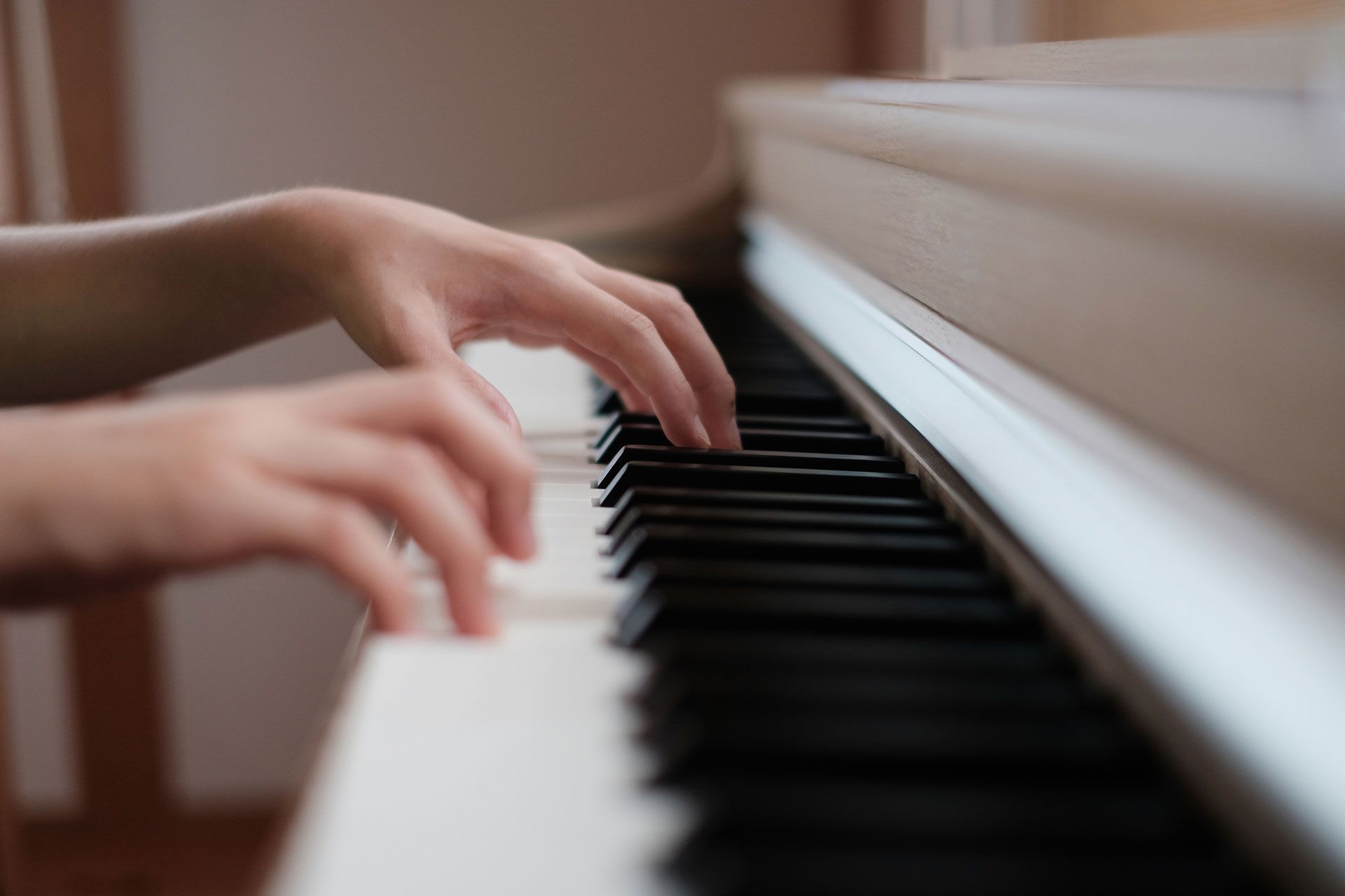 A person is playing a piano with their hands on the keys.