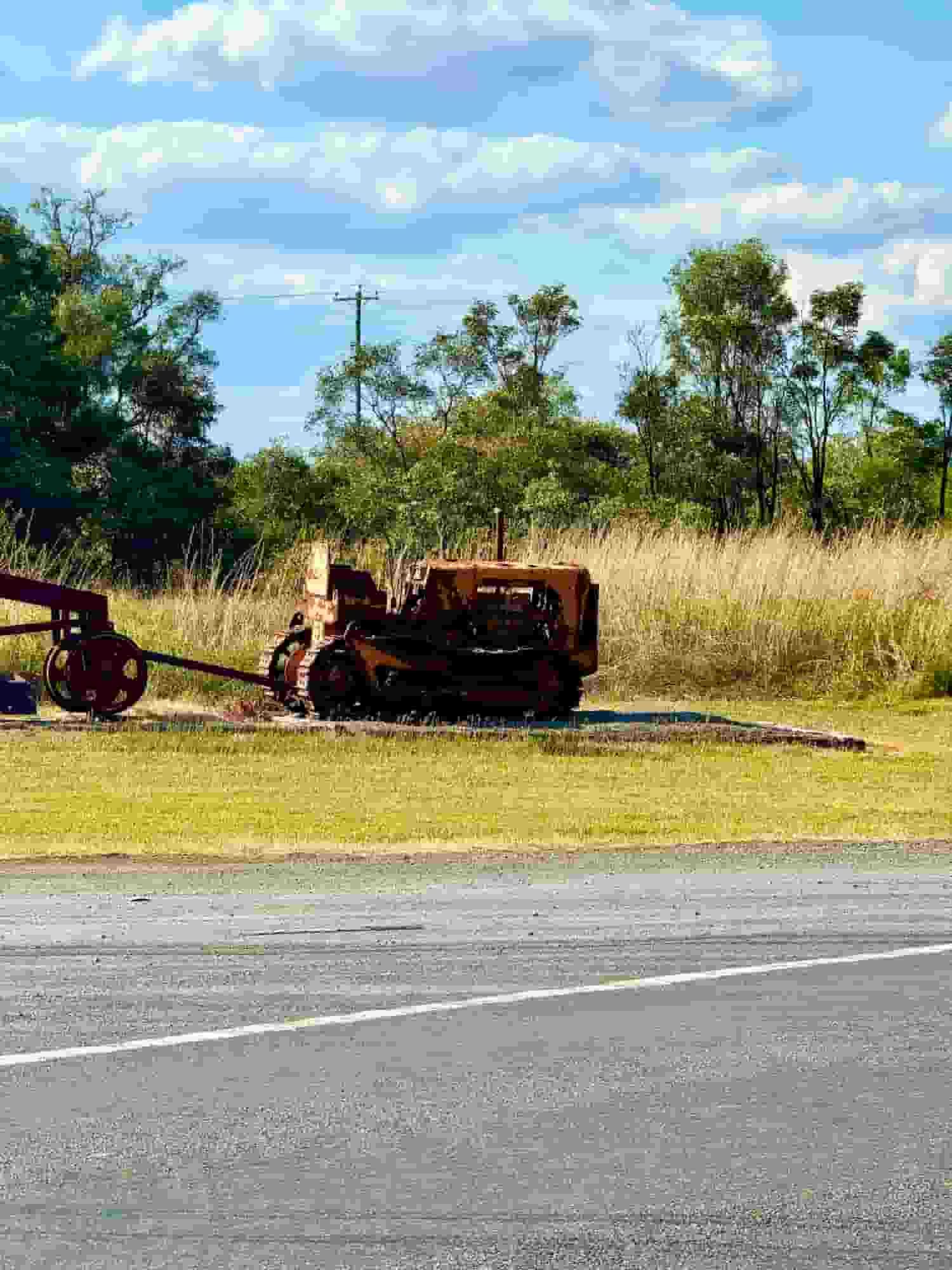 An Old Rusty Tractor is Parked in a Grassy Field Next to a Road — Aspire Diesel In Moura, QLD