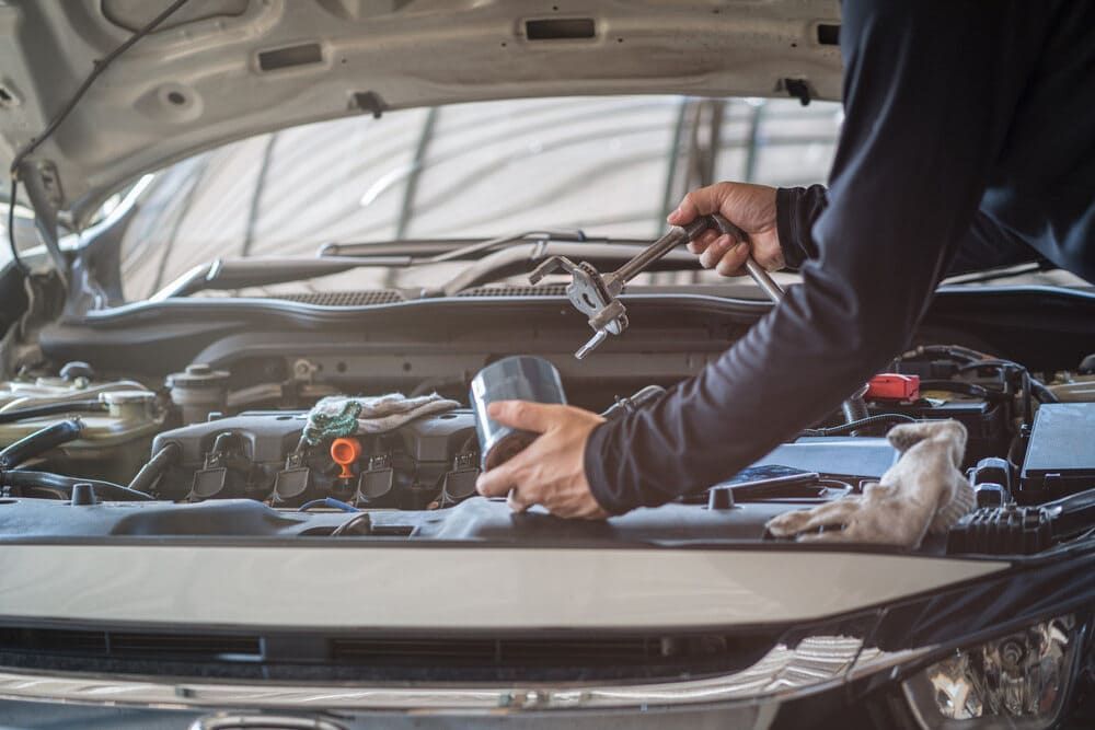 A Man Is Working On The Engine Of A Car With A Wrench — Aspire Diesel In Gracemere, QLD