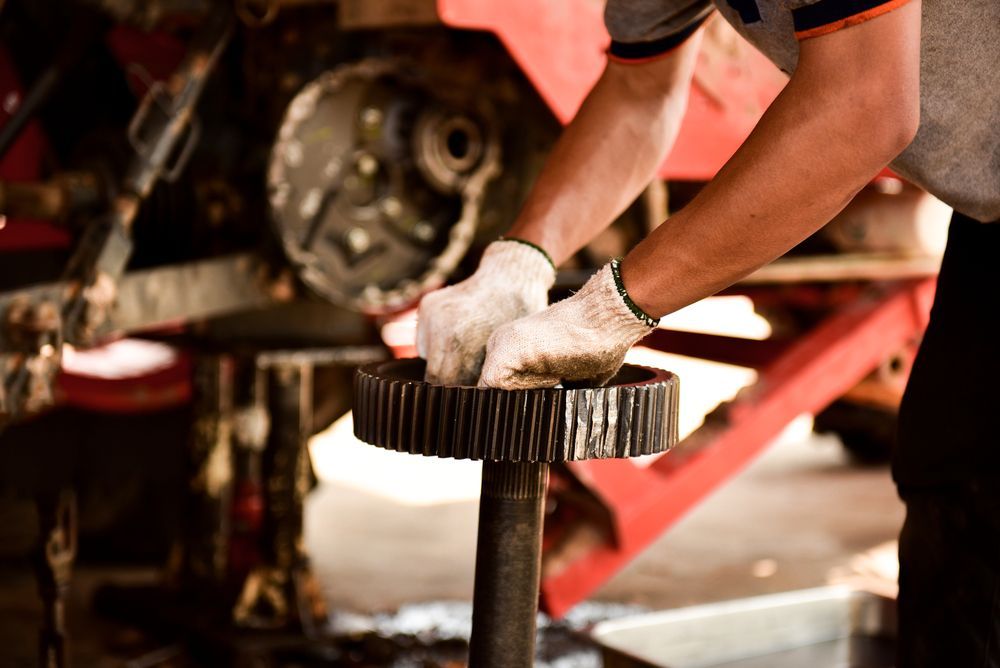 A Worker Wearing Work Gloves Cleans a Dark, Cylindrical Metal Gear — Aspire Diesel In Moura, QLD