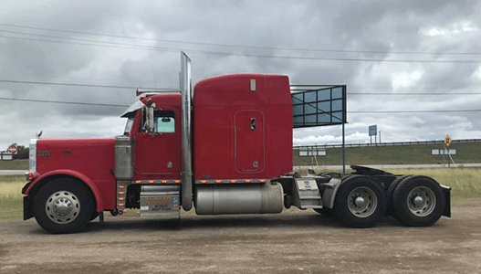 A red semi truck is parked on the side of the road.