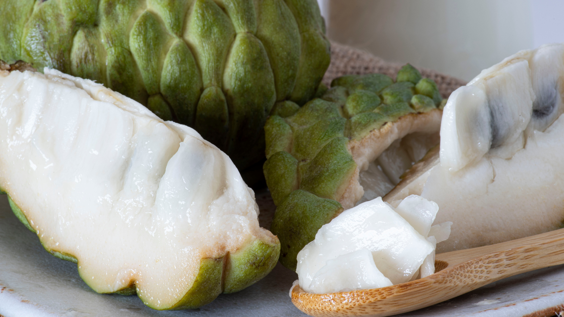 Um close de uma fruta-do-conde em um prato com uma colher de pau.