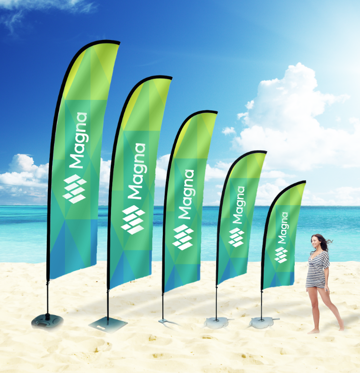 Een vrouw staat op een strand naast een rij vlaggen met de tekst magna