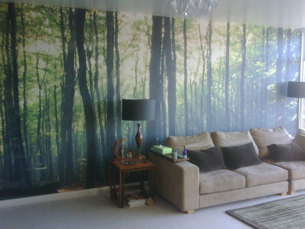 Een woonkamer met een bank en een foto van bomen aan de muur