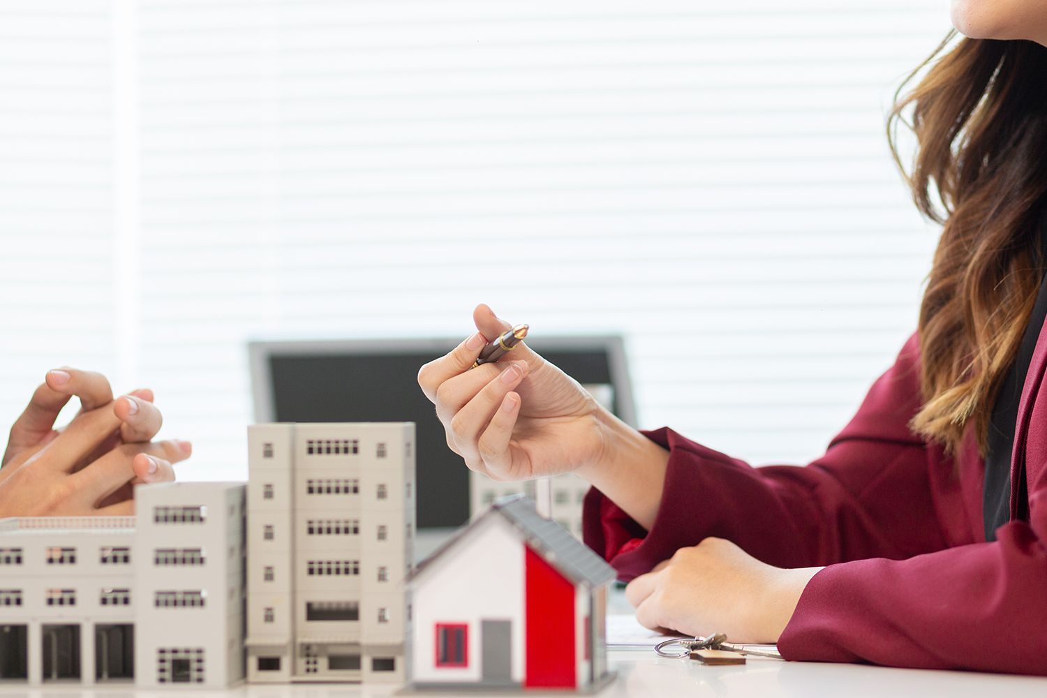 Real estate agent hands a house key to a client over miniature buildings. Real estate agent hands a house key to a client over miniature buildings.