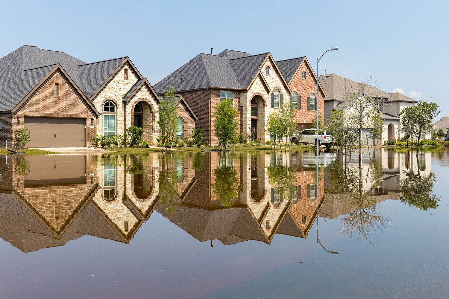 Suburban homes reflected in floodwater on a sunny day. Suburban homes reflected in floodwater on a sunny day.
