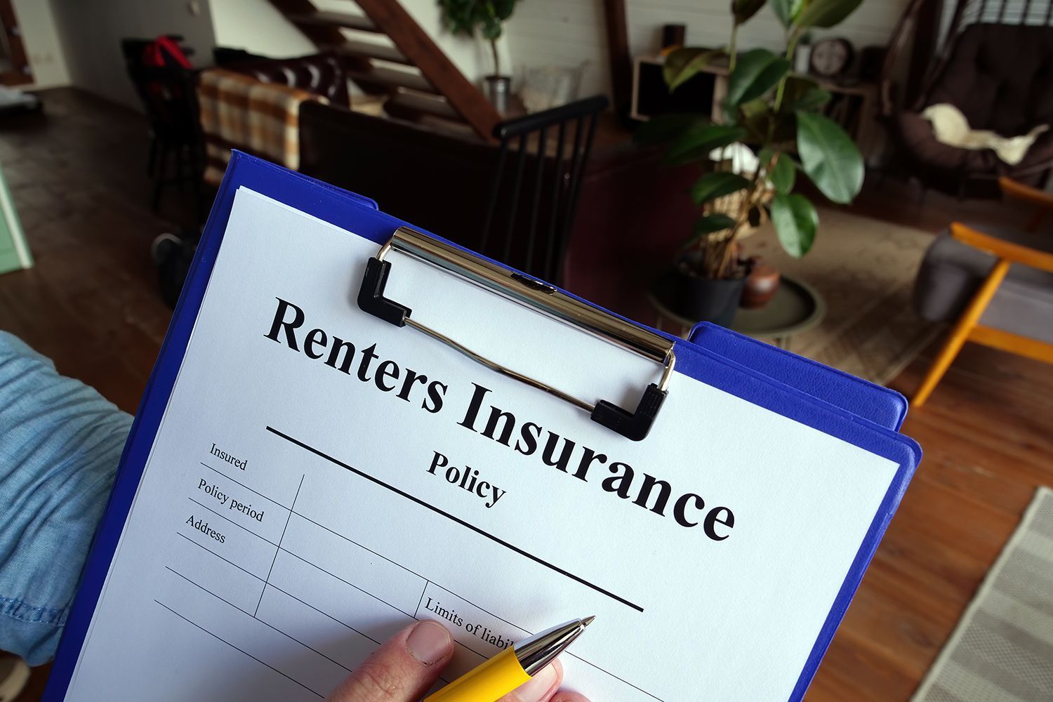 Person signing a renters insurance policy on a clipboard, indoors. Person signing a renters insurance policy on a clipboard, indoors.