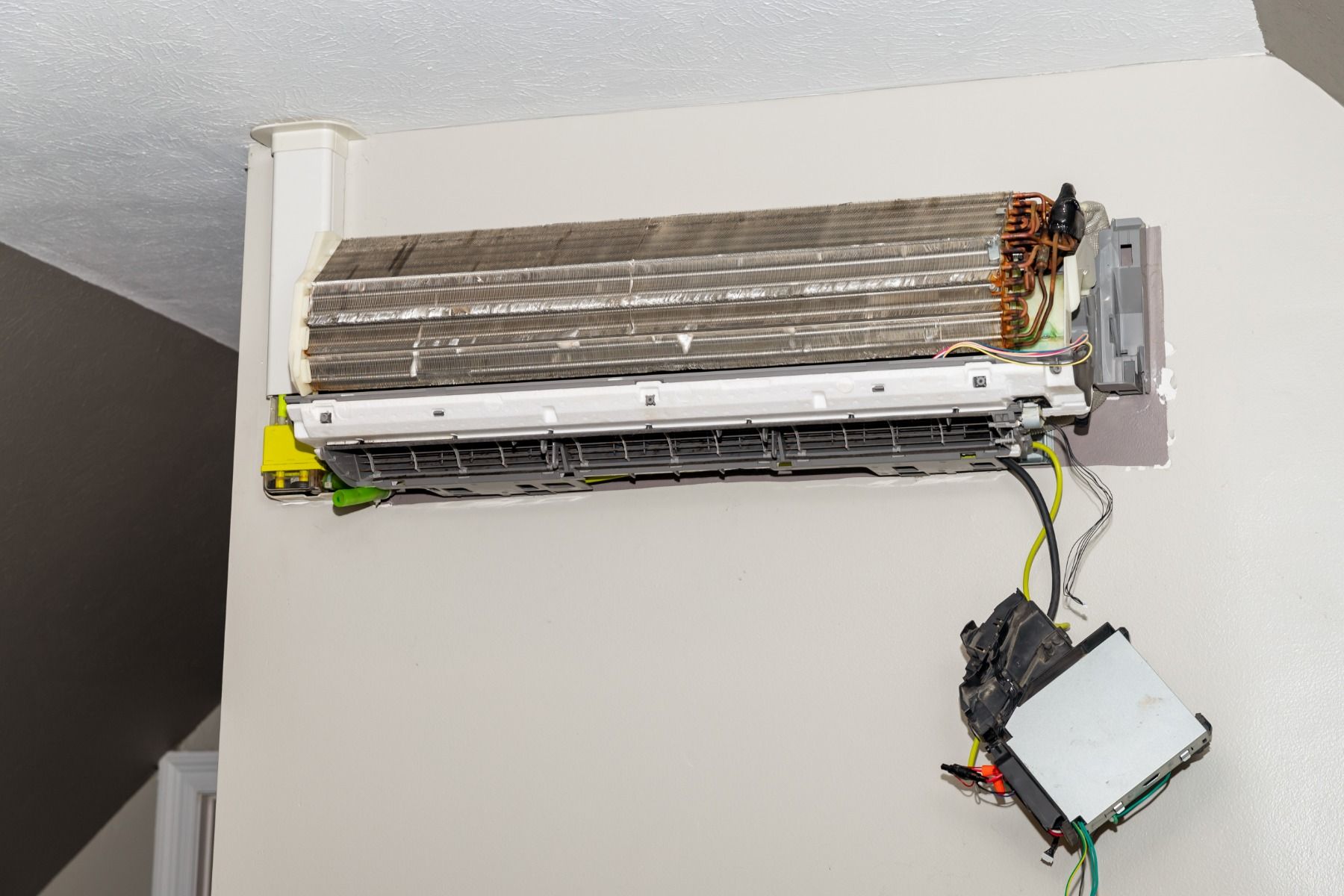 A dirty air conditioner is sitting on a white wall.