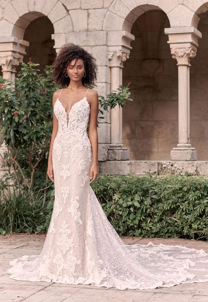 Tuscany Royal by Maggie Sottero. Sparkly lace sheath bridal dress with illusion lace train. All-around shimmer and illusion makes this sparkly lace sheath bridal dress a stunner from any angle.