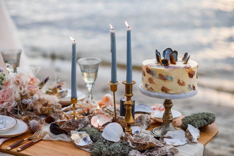 Wedding celebration table setting on the beach with candles and cake