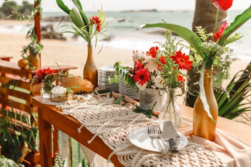 Wedding celebration table setting on the beach with red floral arrangement
