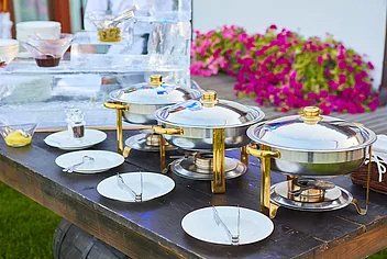 a wooden table topped with plates and pots of food .