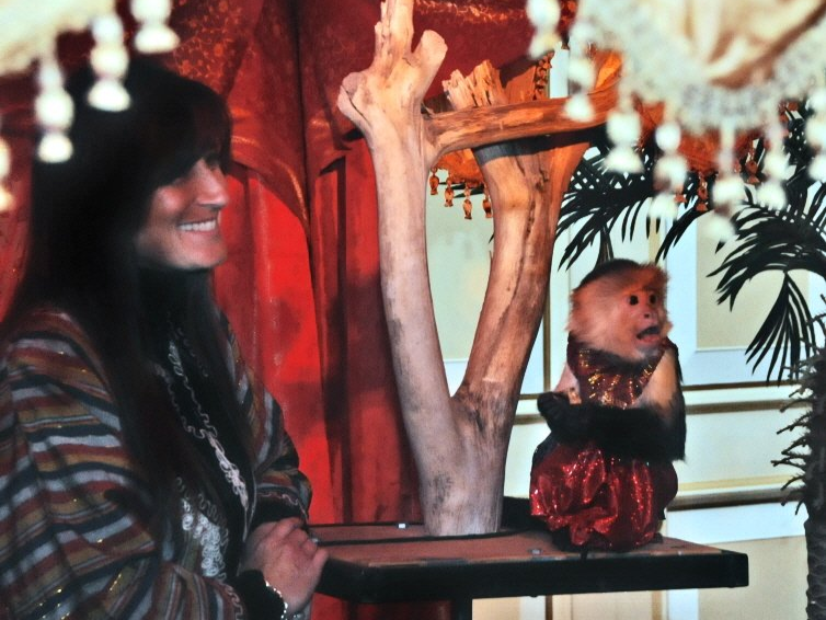 a woman stands next to a monkey wearing a red dress