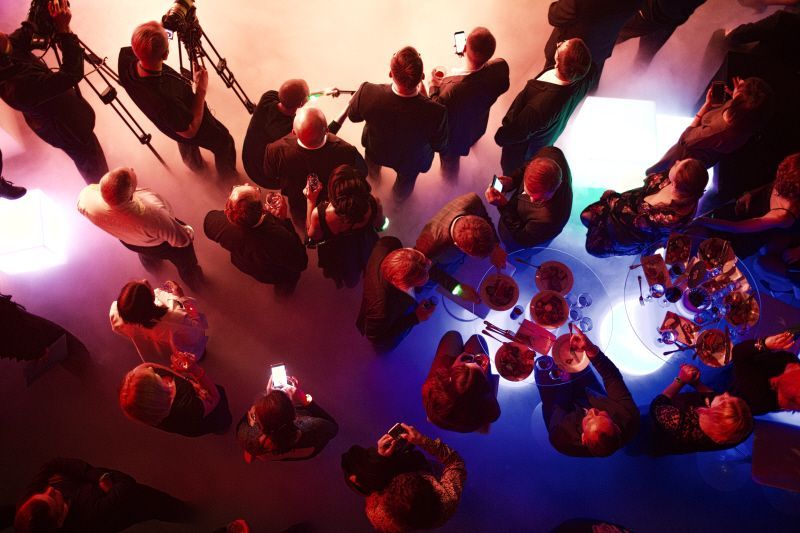  group of people in professional attire are gathered around tables with plates of food
