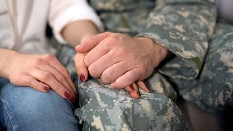 A couple holding hands. The man is in a military uniform.