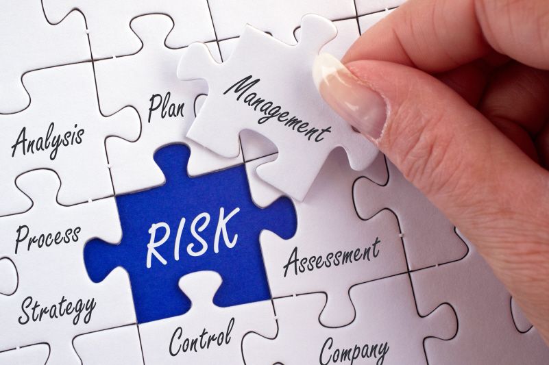 a puzzle with a blue risk piece about to be covered with a white management puzzle piece.