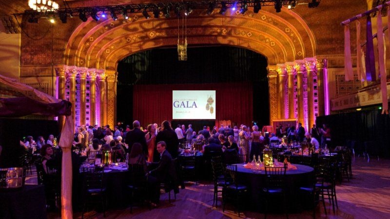 Galas and fundraising event ballroom setting showing table settings and stage setup with screen