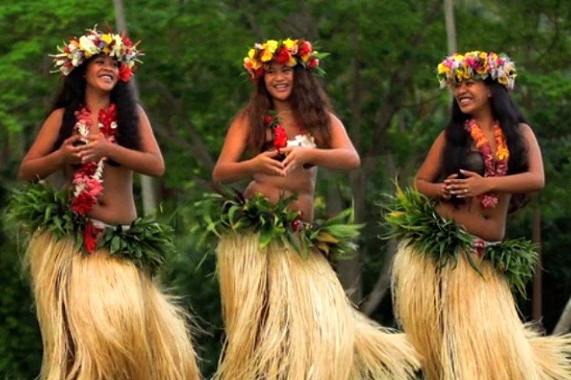 Three Hawaiian Dancers dressed in grass skirts and traditional outfits