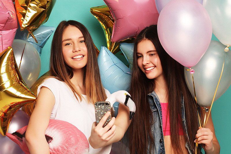 Teen birthday party with two teens holding balloons and taking selfie