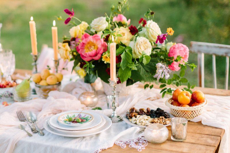Romantic styled picnic table setting with flower arrangement and candles