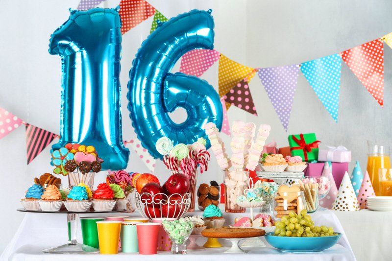 Teen birthday party food setup with large numeric balloons showing 16