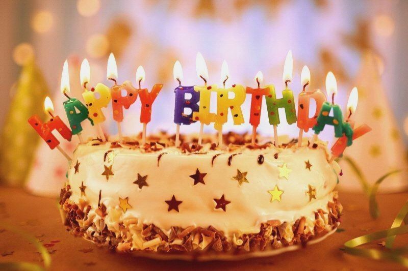 Birthday Cake with Lit Candles Saying Happy Birthday