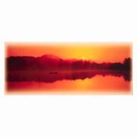 Orange sunset over a mountain range reflected in calm water.