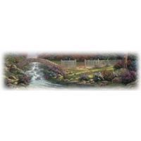 Stone bridge over a flowing creek in a serene garden. White picket fence in background.