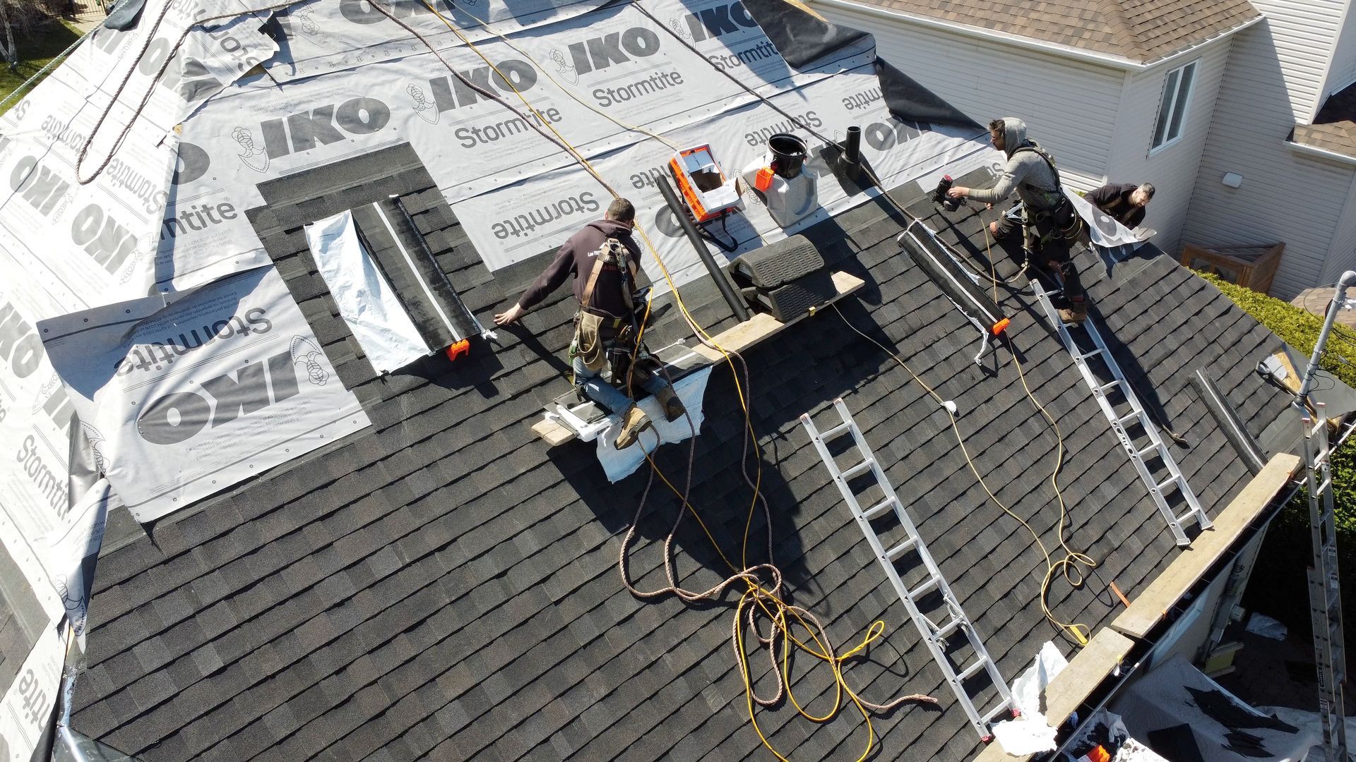 A man is holding a toolbox on top of a roof.