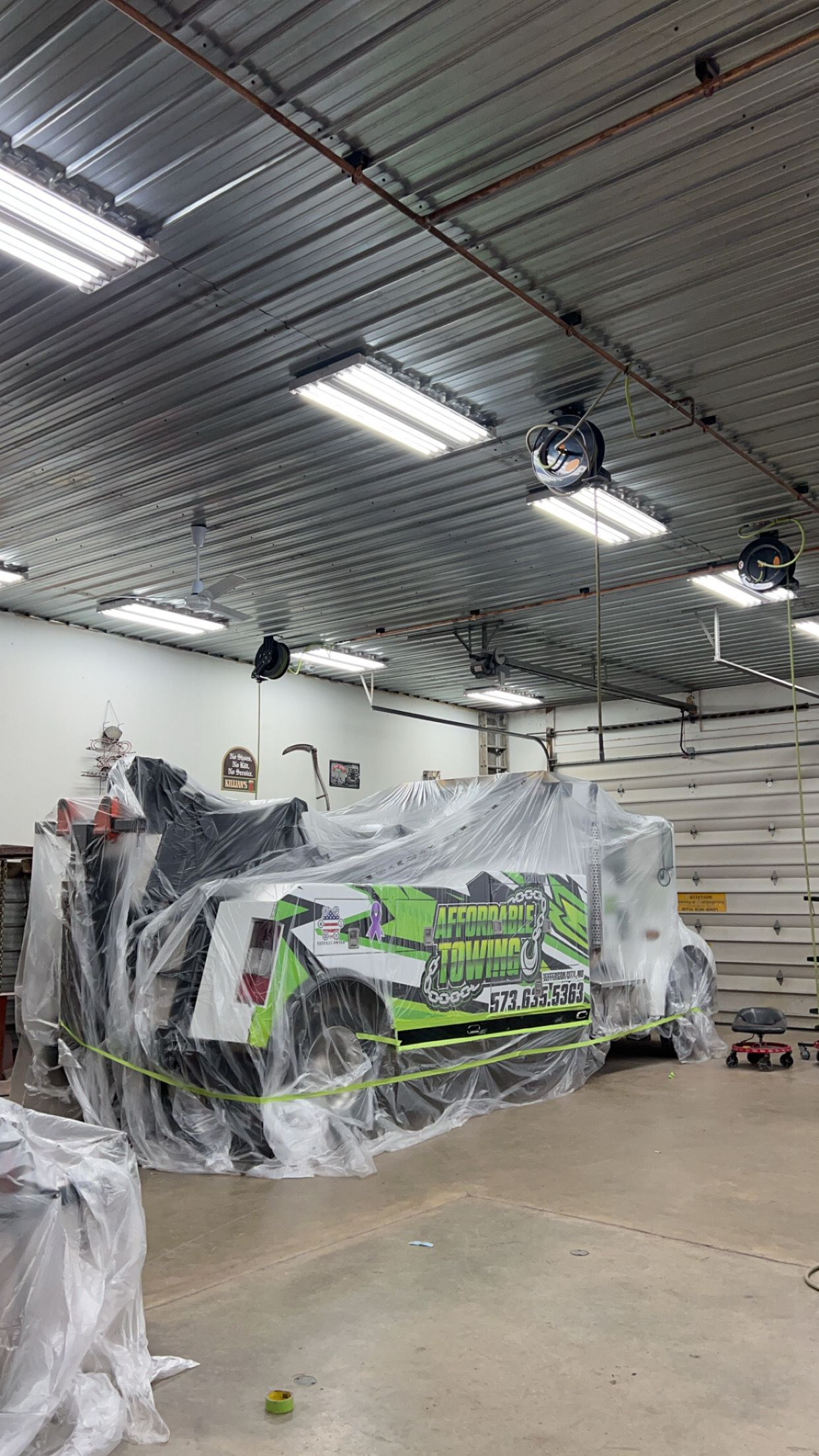 An Affordable Towing Truck Covered & Parked in Lutz's Garage, an Auto Body Shop in Mid-MO.