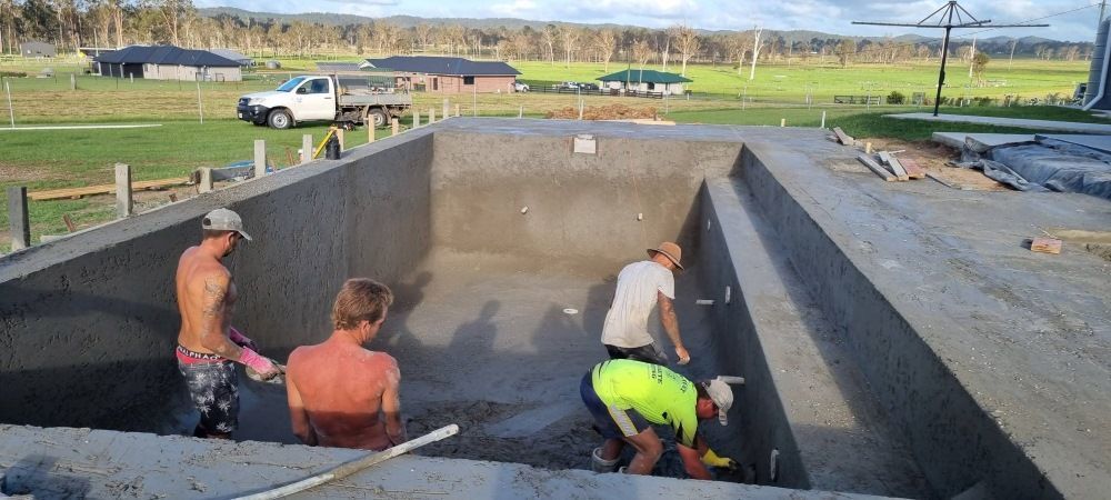 A Group Of Men Are Working On A Swimming Pool — CJB Pools in Gympie, QLD
