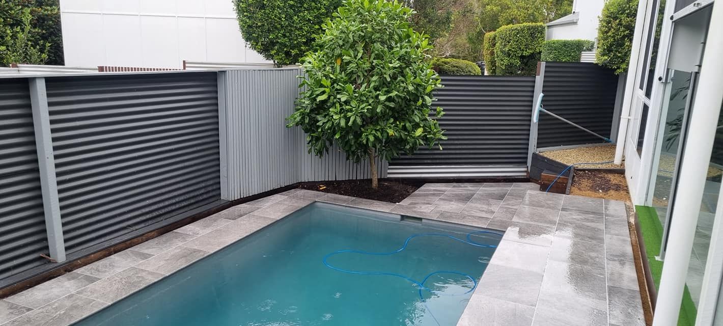 A Small Swimming Pool Surrounded By A Fence And A Tree In A Backyard — CJB Pools in Gympie, QLD