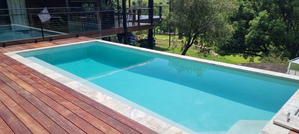 A Large Swimming Pool Is Sitting On Top Of A Wooden Deck — CJB Pools in Gympie, QLD