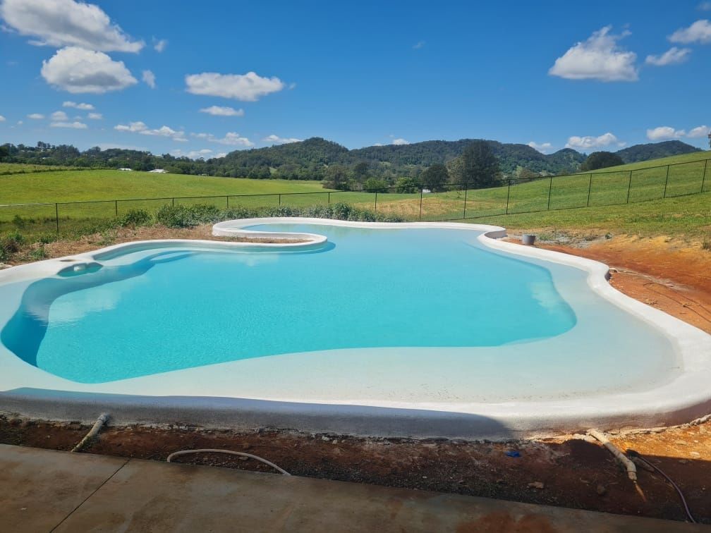 A Large Swimming Pool With Mountains In The Background — CJB Pools in Gympie, QLD