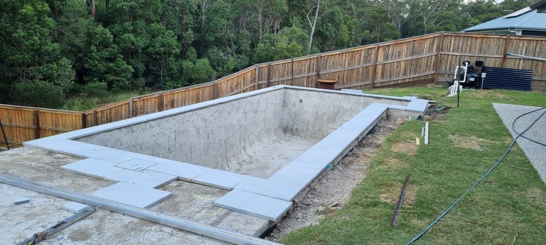 A Large Swimming Pool Is Being Built In A Backyard — CJB Pools in Gympie, QLD