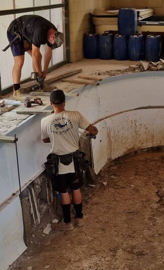 A Man is Using a Hammer to Break Up Concrete — CJB Pools in Gympie, QLD