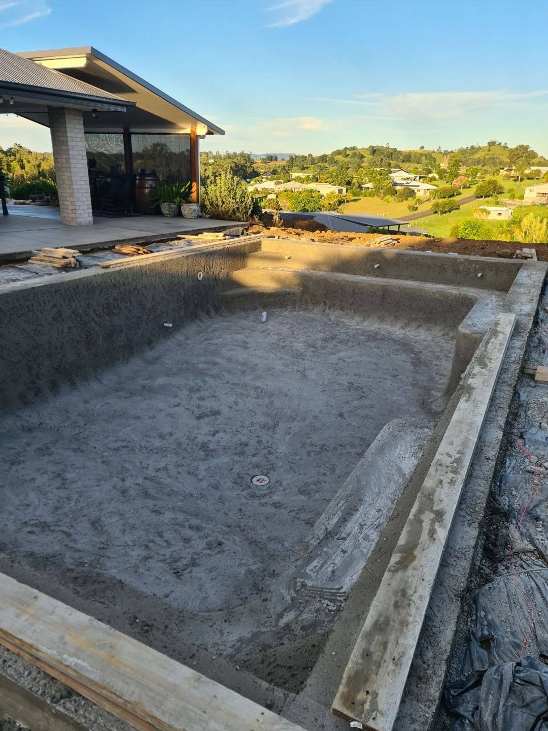 A Man is Pouring Concrete Into a Pool — CJB Pools in Gympie, QLD