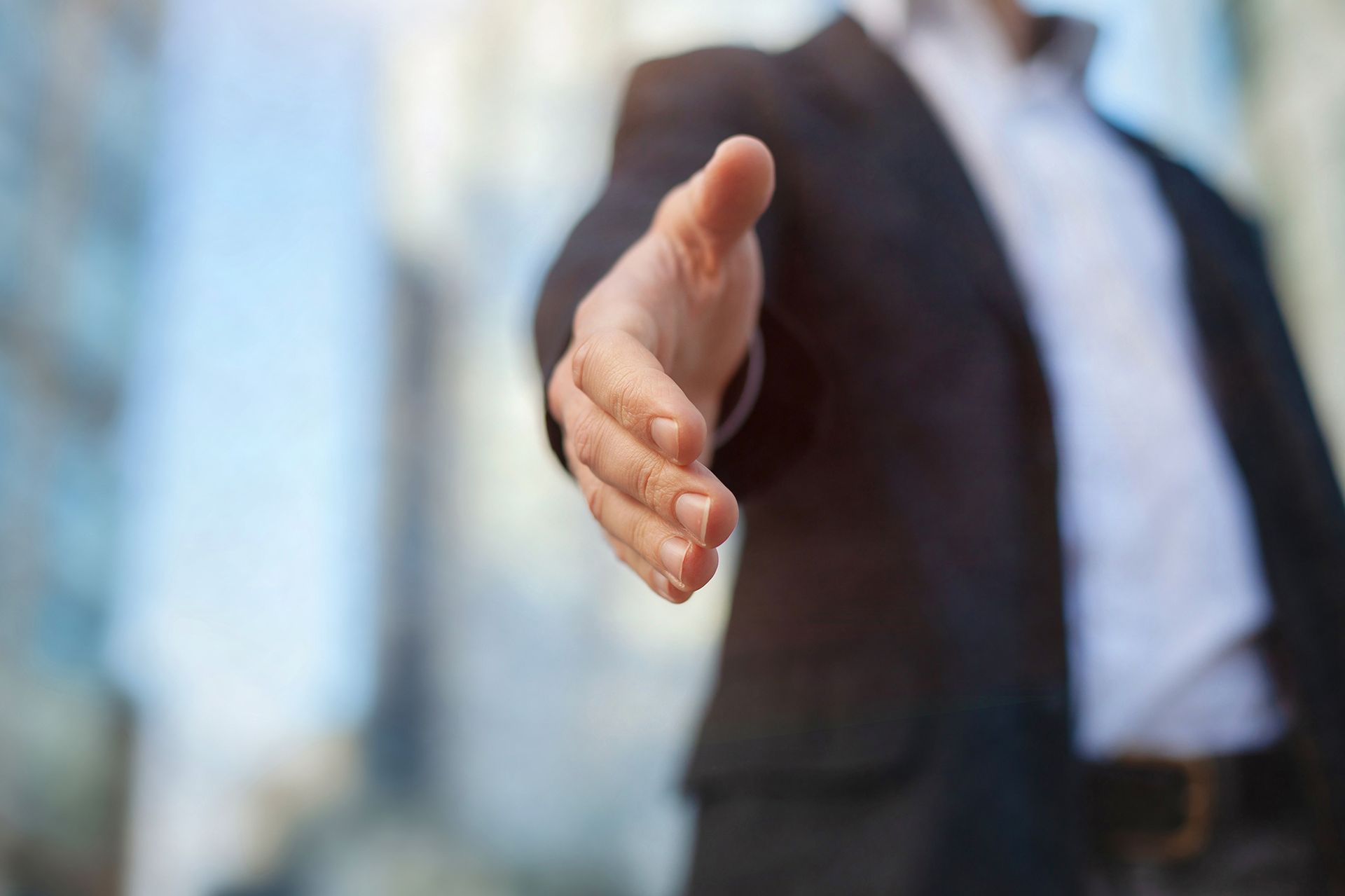 Man in suit extending hand for a handshake.