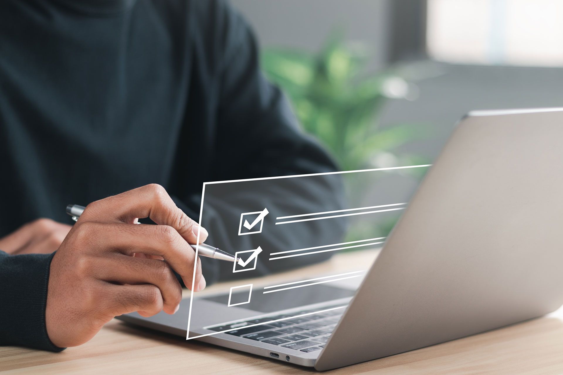 Person using a pen to check off boxes on a digital checklist overlaid on a laptop.