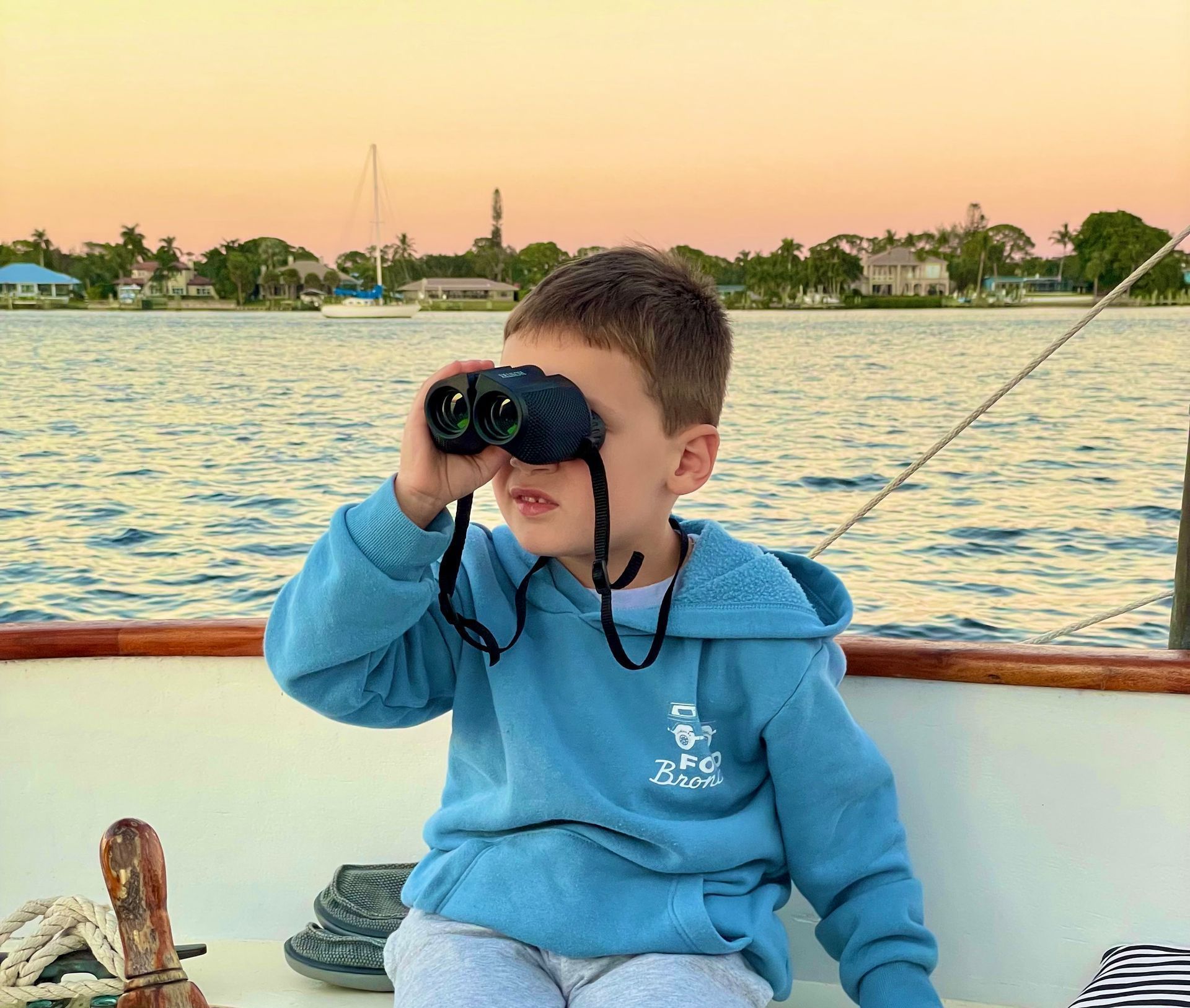A young passenger is looking for wildlife with binoculars on a sailing adventure