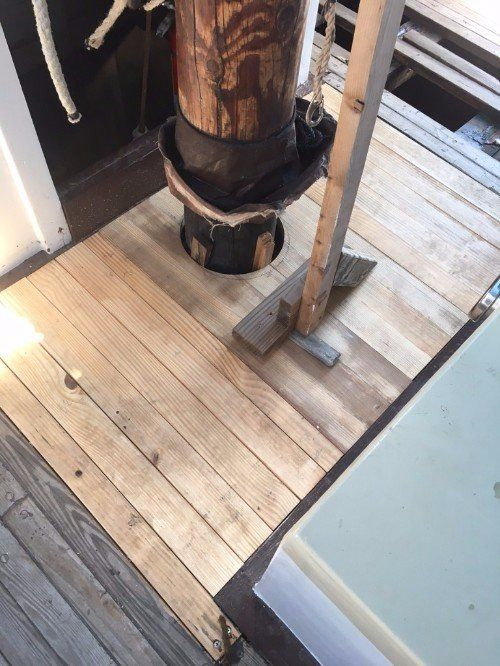 A wooden deck with a wooden mast in the middle.