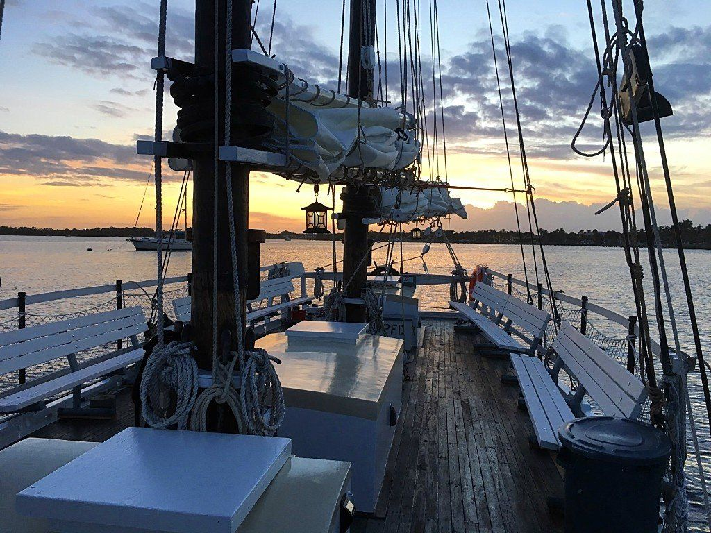 A sailboat is docked in the water at sunset.