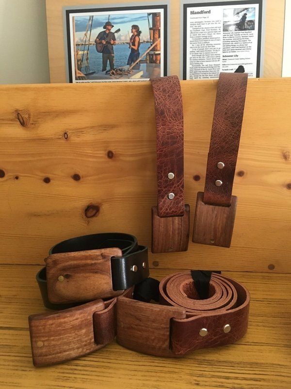 Three wooden belts are sitting on a wooden table.