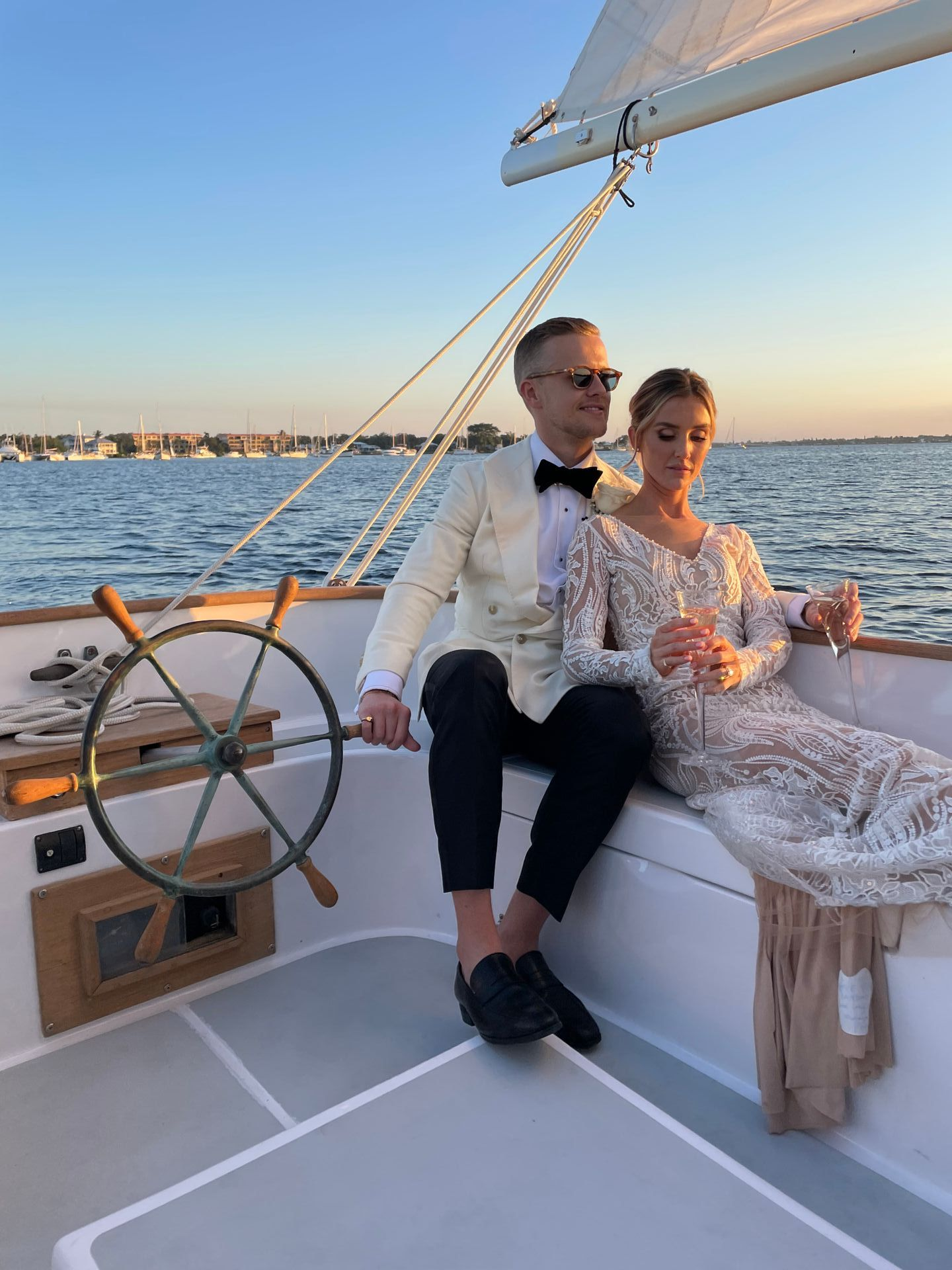 A bride and groom are sitting on a boat holding champagne glasses.
