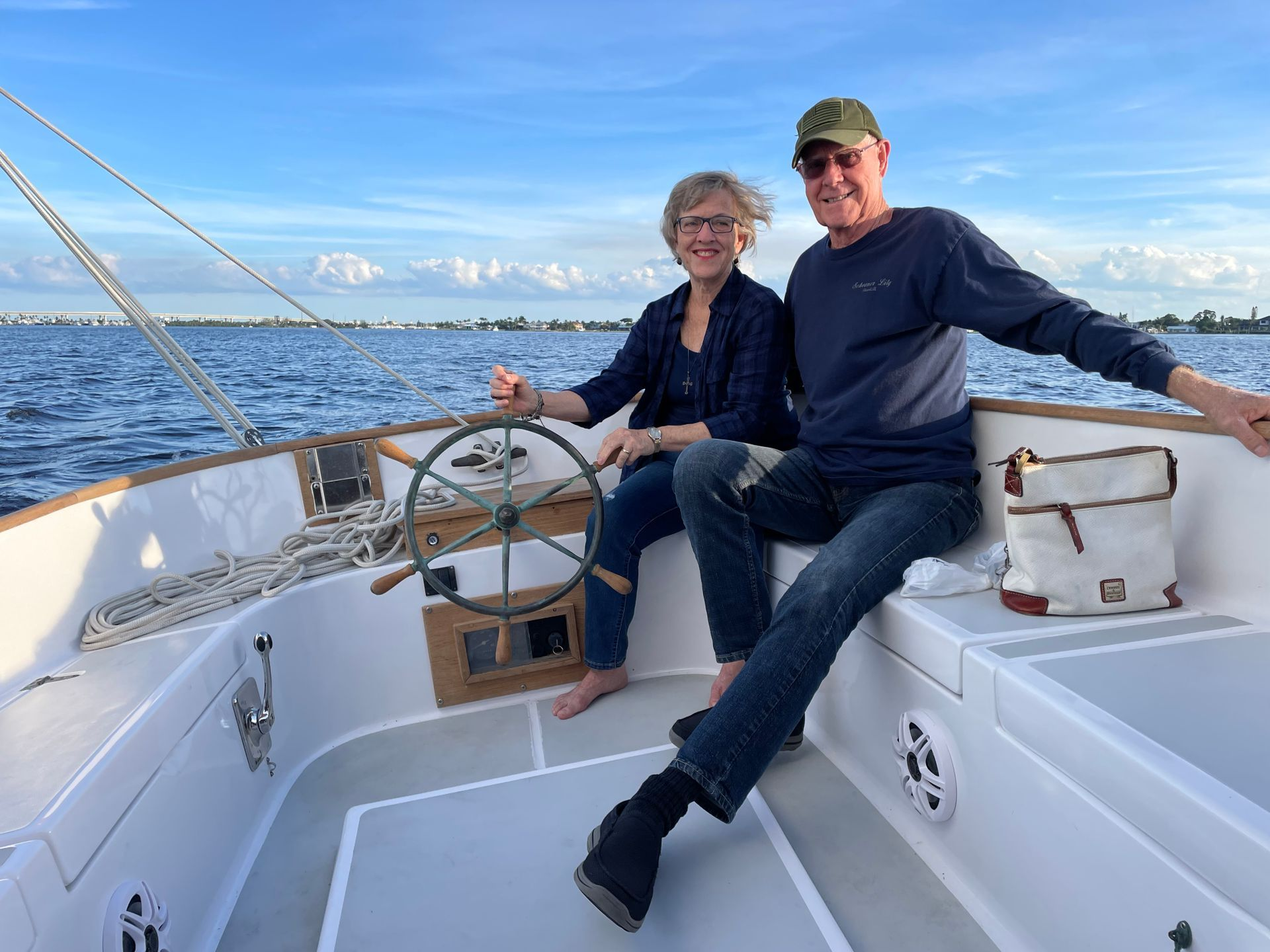 A man and a woman are sitting on the deck of a sailboat. Private charter on catboat