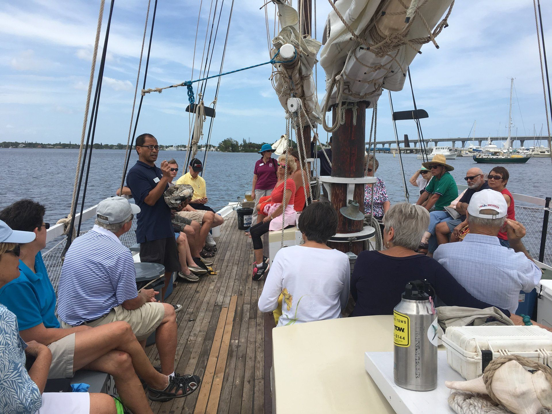 A group of people are sitting on the deck of a sailboat.