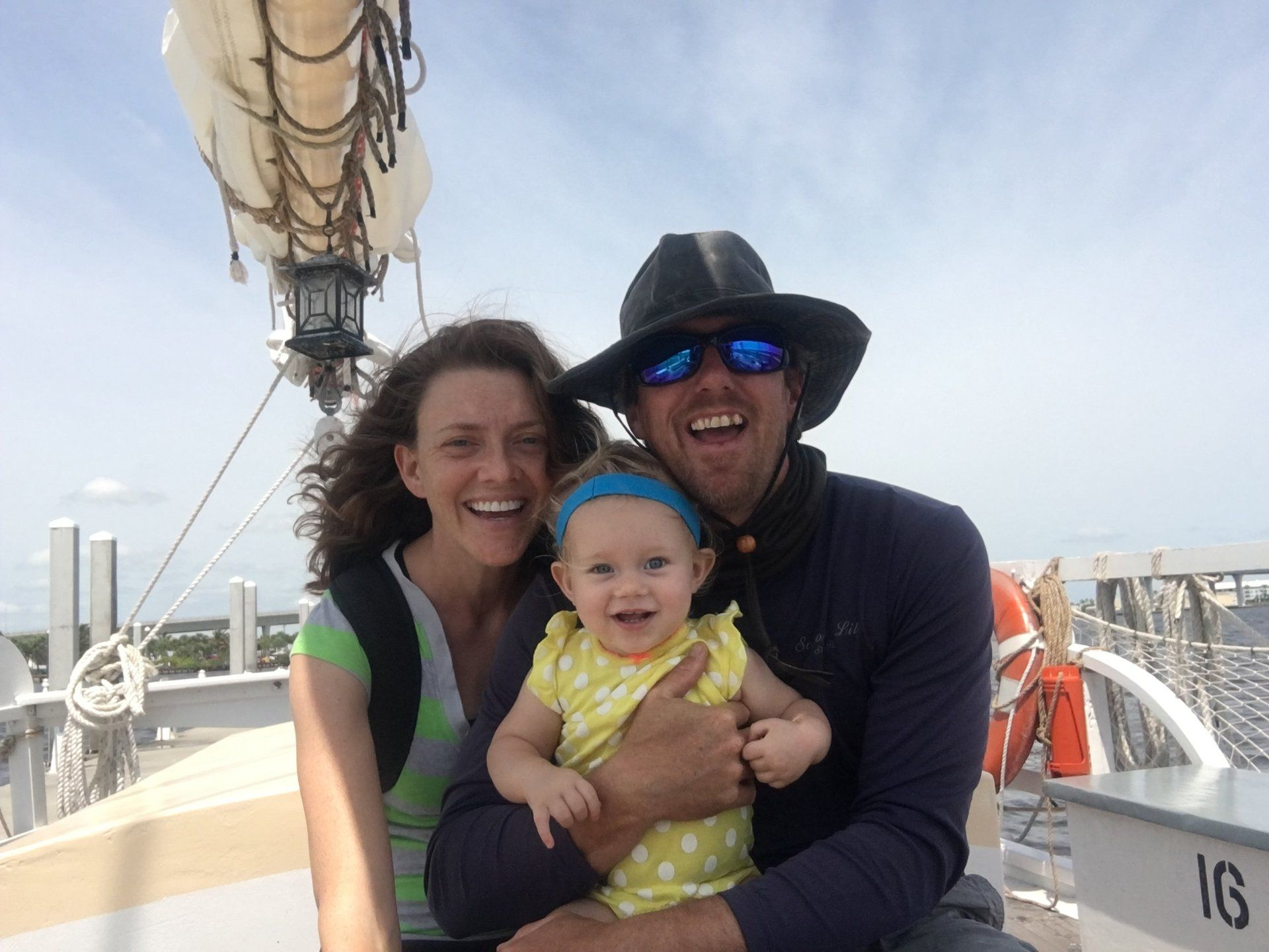 A man and woman are holding a baby on a boat. Owners of Treasure Coast Sailing adventures on their first boat, Schooner Lily