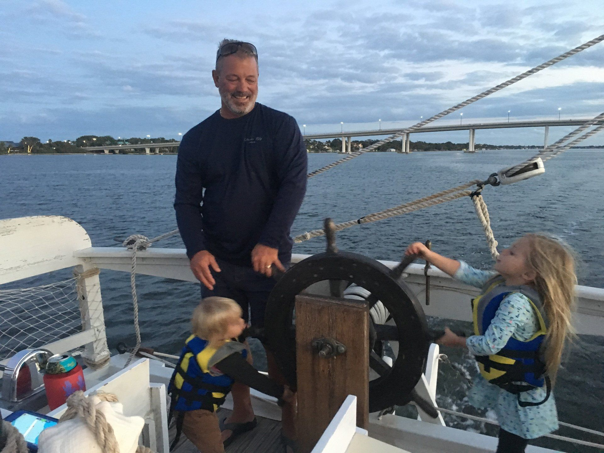 A man and two children are steering a boat in the water. Private Charter on Certified USCG Passenger Vessel